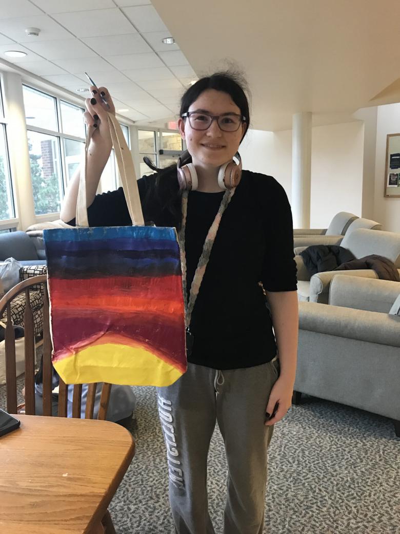 A student holds the freshly painted tote bag.